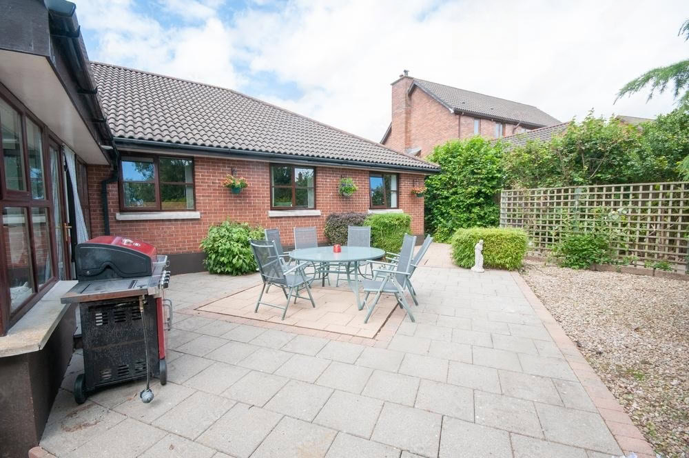 Outdoor patio with a table, chairs, and a barbecue grill next to a brick house.