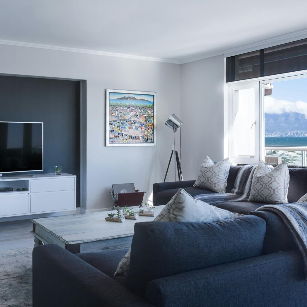 Modern living room with a large TV and a view of a mountain and ocean.