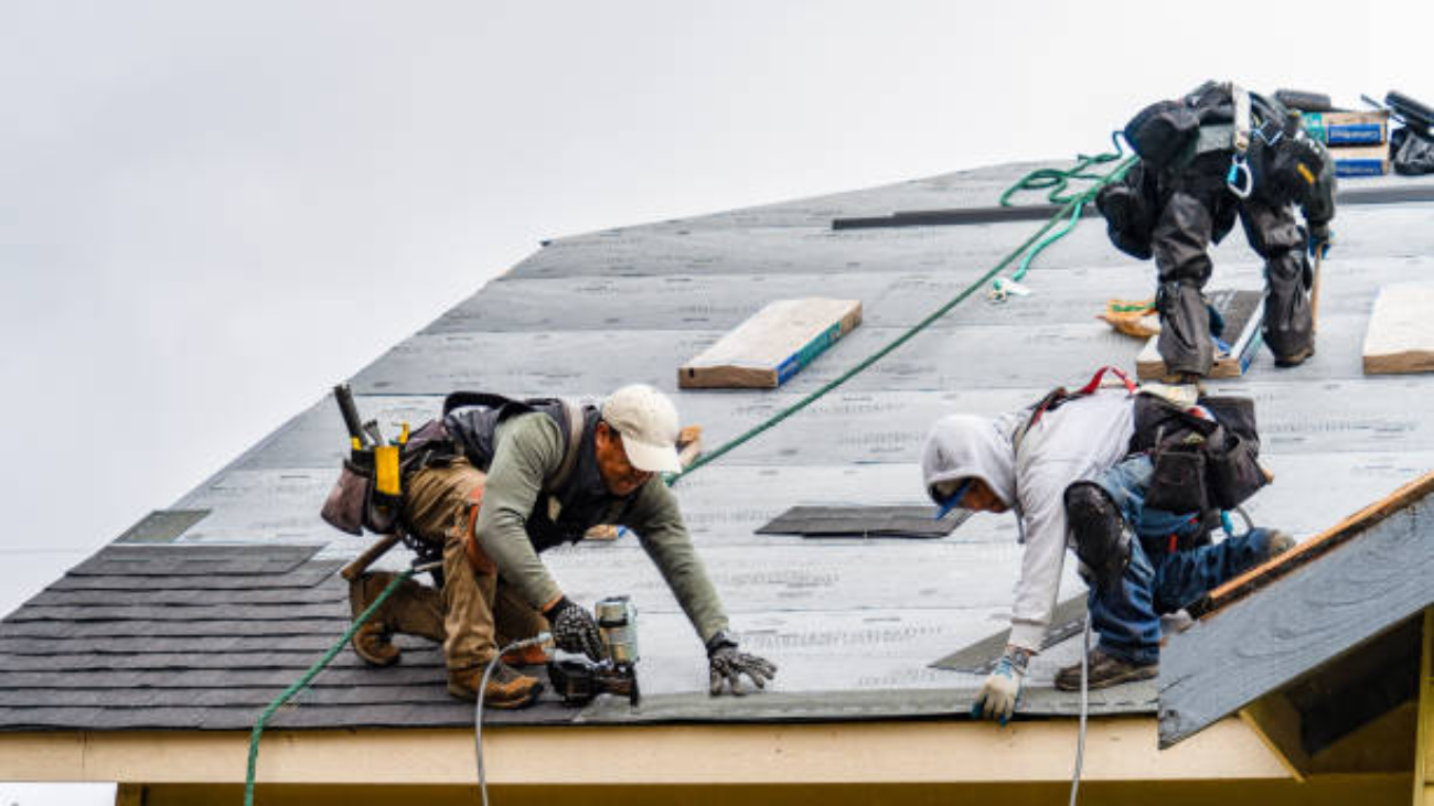 Everett WA. USA - 03-23-2021: Crew Installing New Shingles on Roof on a Rainy Day