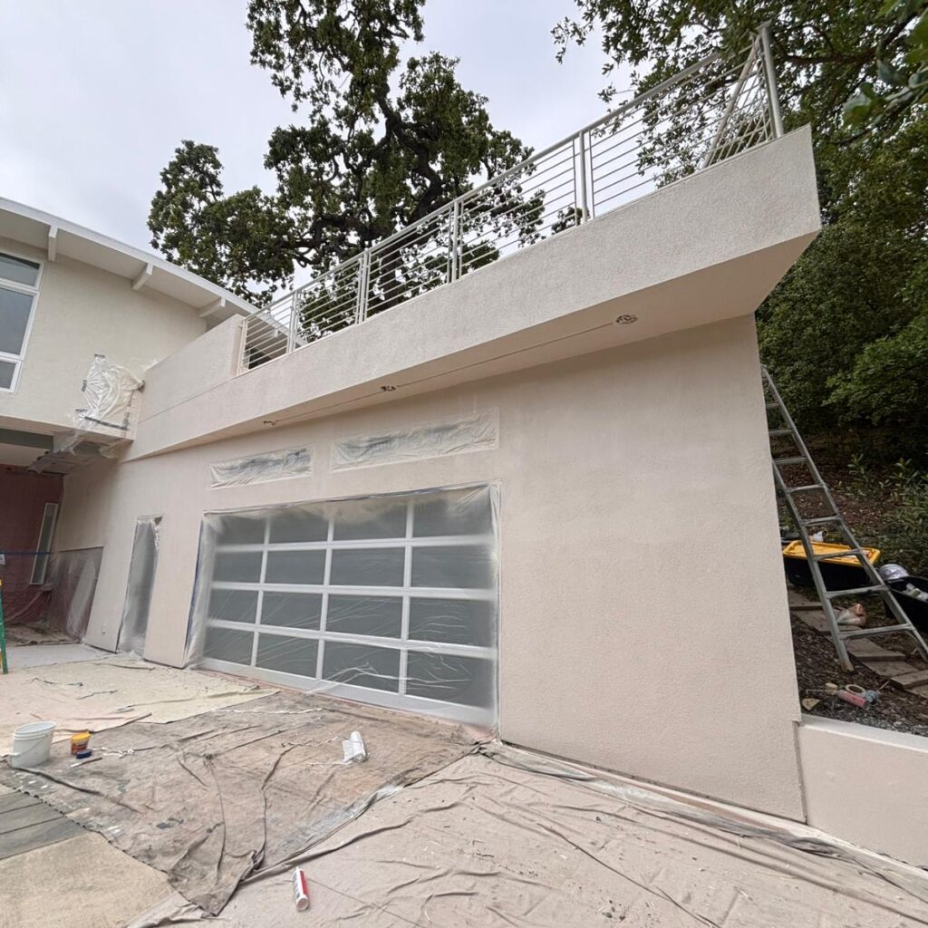 Modern house exterior under construction with garage door covered in plastic.