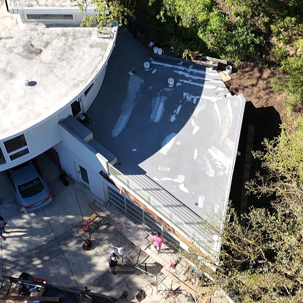 Aerial view of a modern house with a curved roof and a car in the driveway.