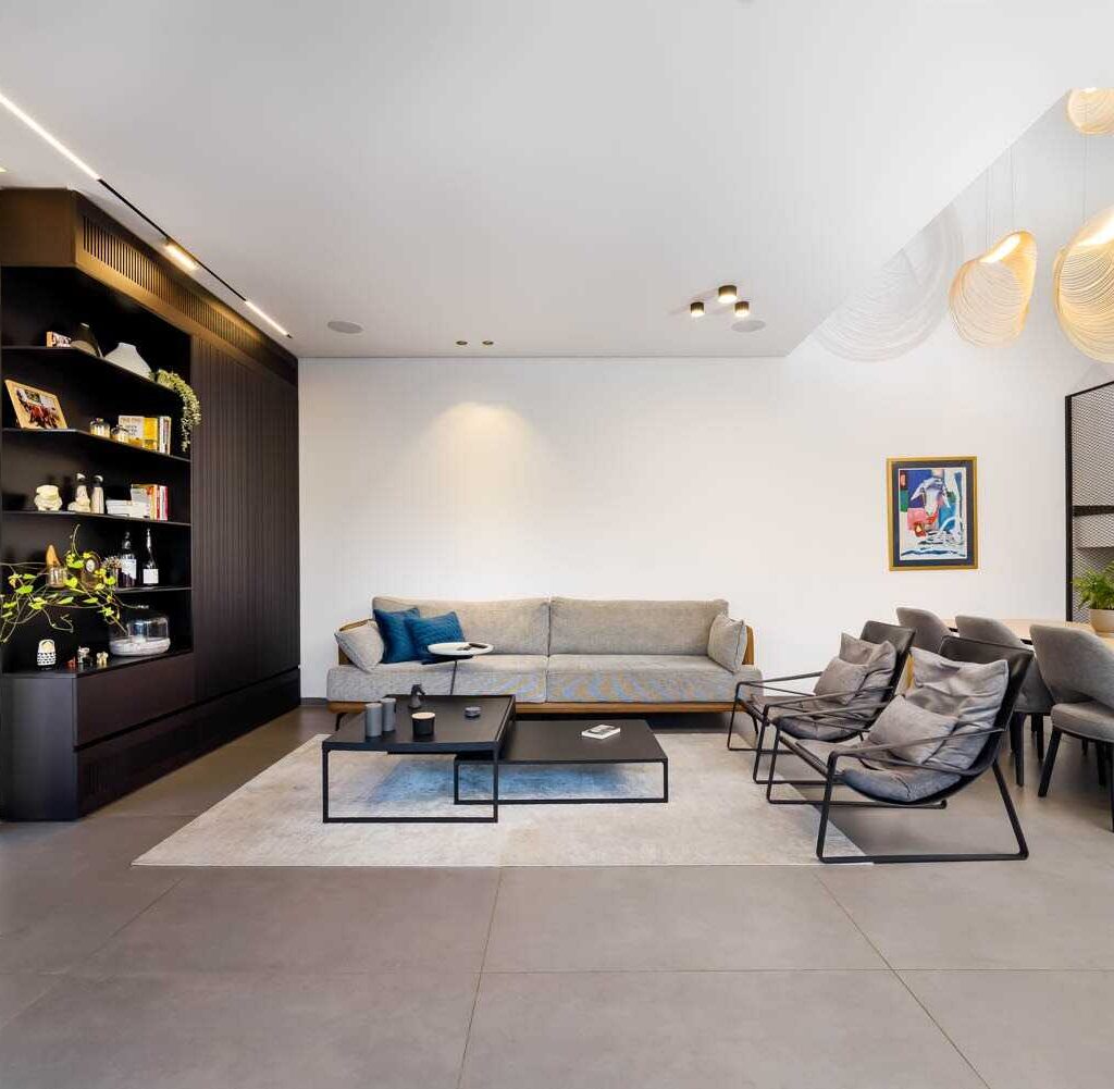 Modern living room with a gray sofa, black coffee tables, and dining area.
