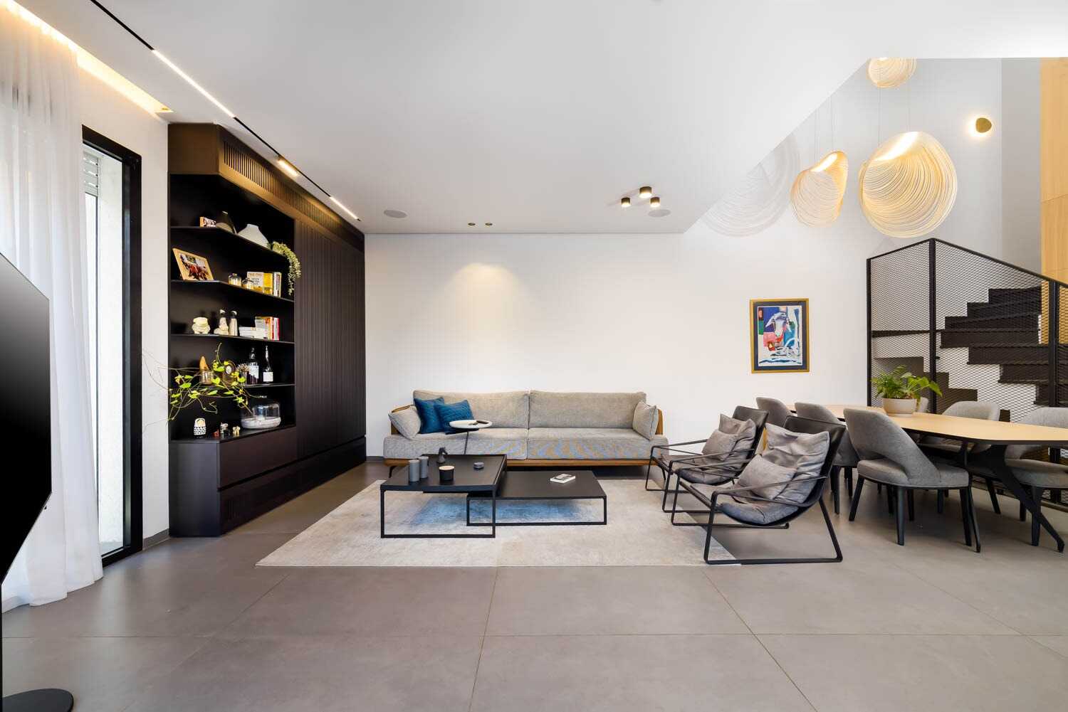 Modern living room with a gray sofa, black coffee tables, and dining area.