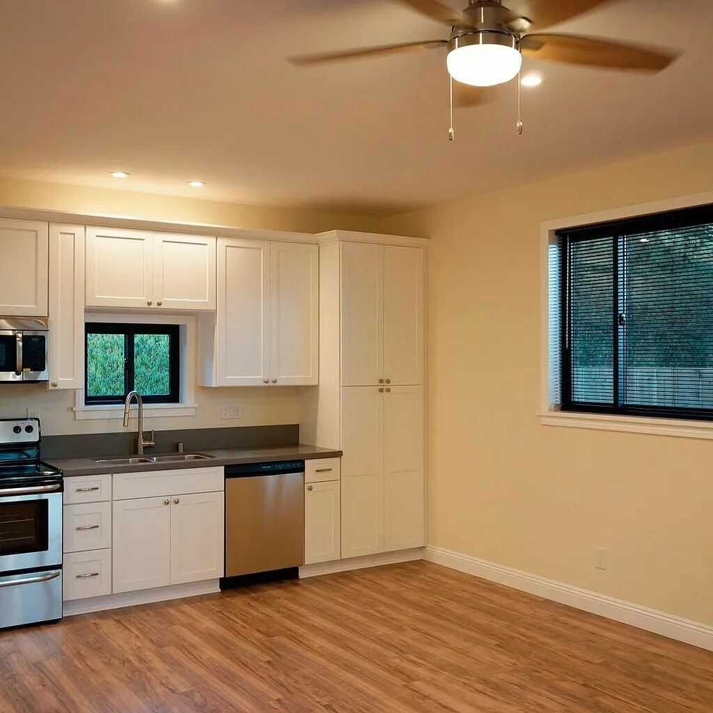 Modern kitchen with white cabinets, stainless steel appliances, and wood flooring.