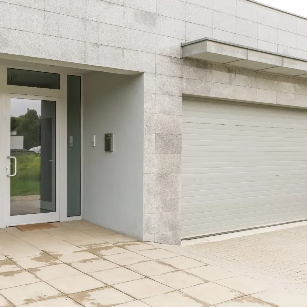 Modern house exterior with a garage door and glass entrance.