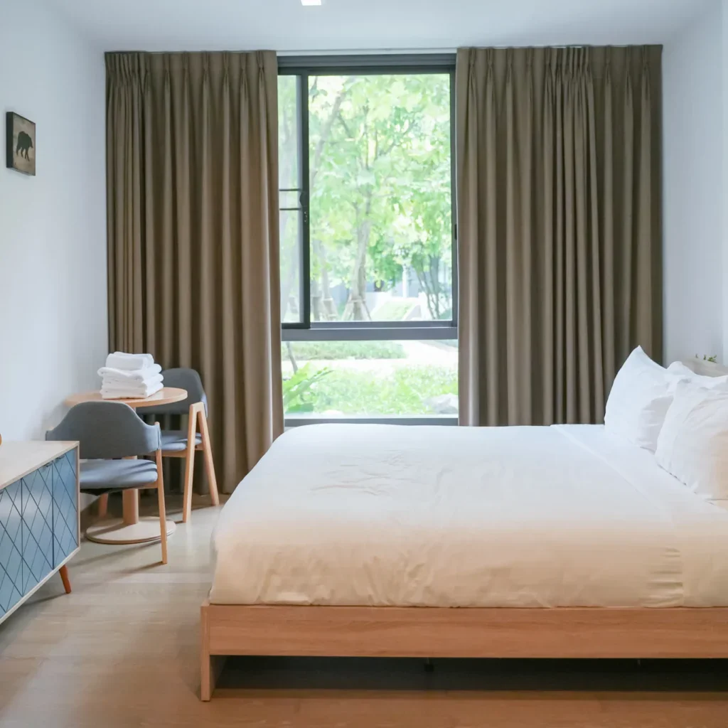 Bright bedroom with a large bed, wooden furniture, and a window.