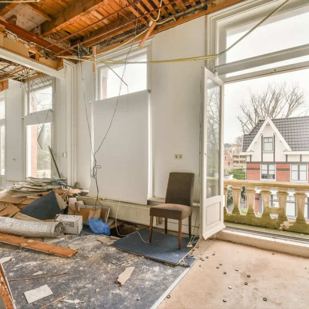 Interior of a room under renovation with exposed ceiling and debris