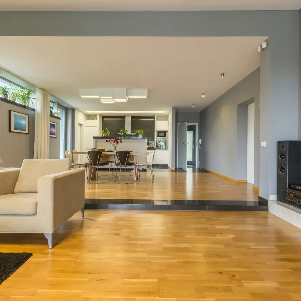 Modern open-concept living room with beige sofa and wooden floors