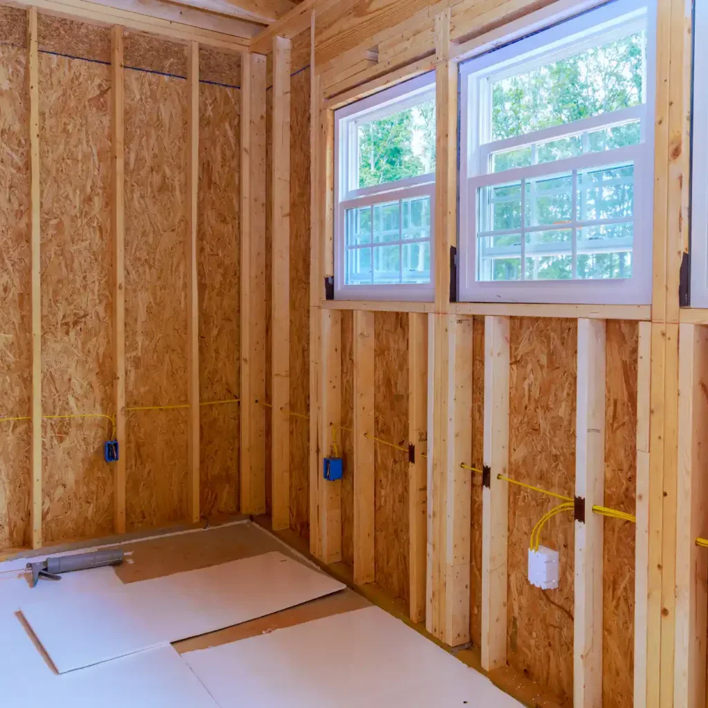 Interior of a room under construction with wooden studs and windows