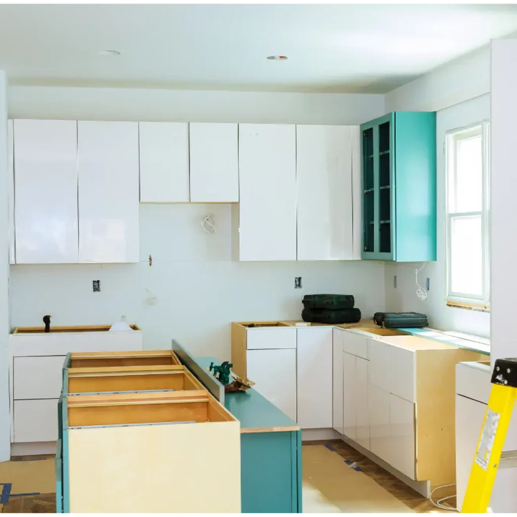 Kitchen under construction with white and teal cabinets, yellow ladder, and tools.