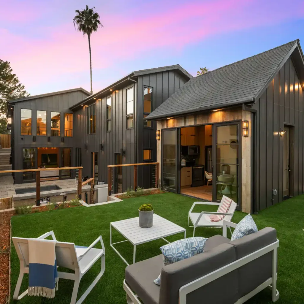 Modern house exterior with a lush green lawn and outdoor seating.