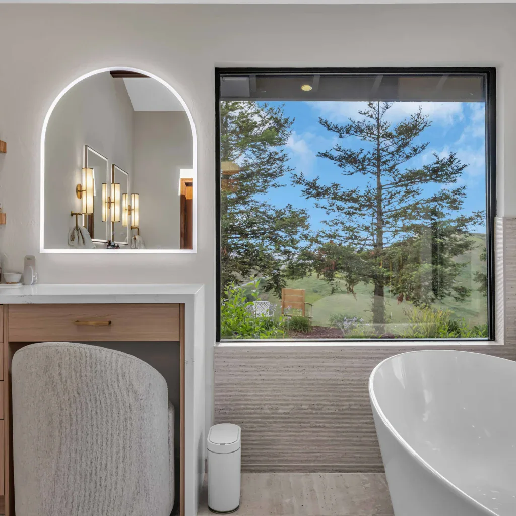 Bright modern bathroom with large windows and a freestanding bathtub.
